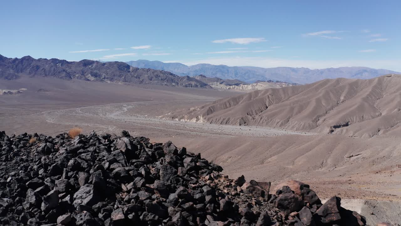 Aerial close-up dolly shot of a rocky desert ridge above the entrance to Death Valley National Park, California. 4K