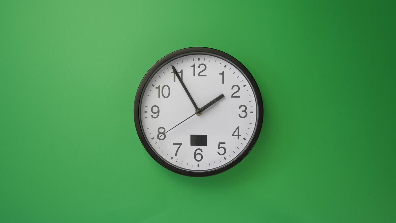 Un orologio da ufficio bianco appeso su sfondo verde, timelapse.