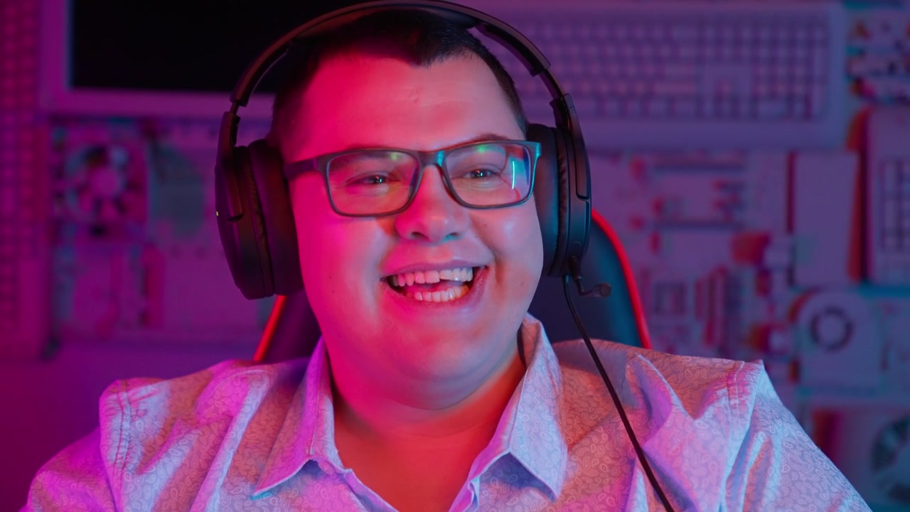 Giovane uomo con cuffie che sorride e ride in una stanza illuminata al neon