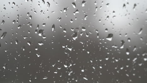 Rain-drops-land-on-a-window-and-trickle-down-the-glass-during-a-rain-storm