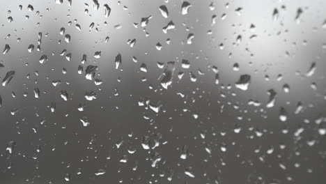 rain drops land on a window and trickle down the glass during a rain storm