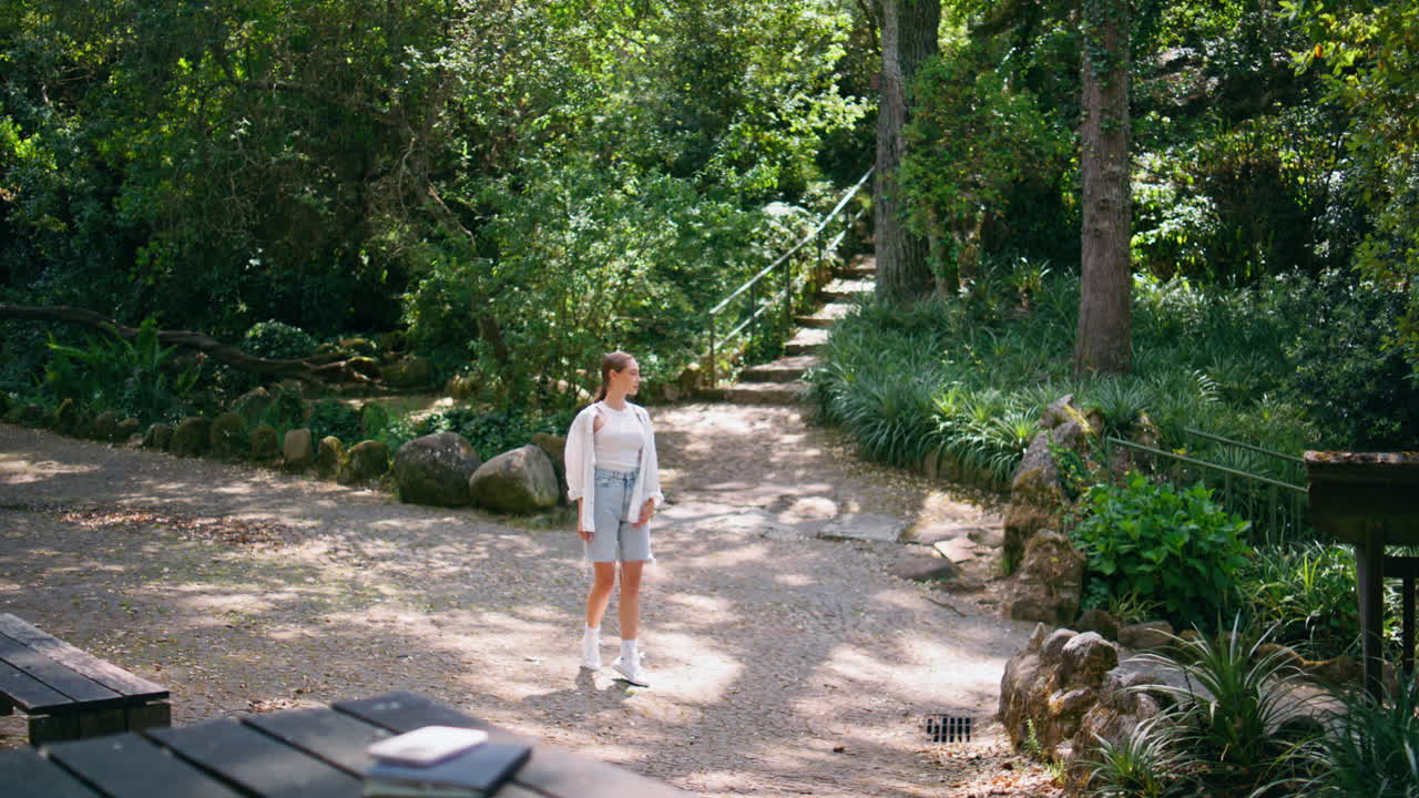 mujer mirando alrededor del bosque lugar de recreación fin de semana soleado. niña parque de relajación