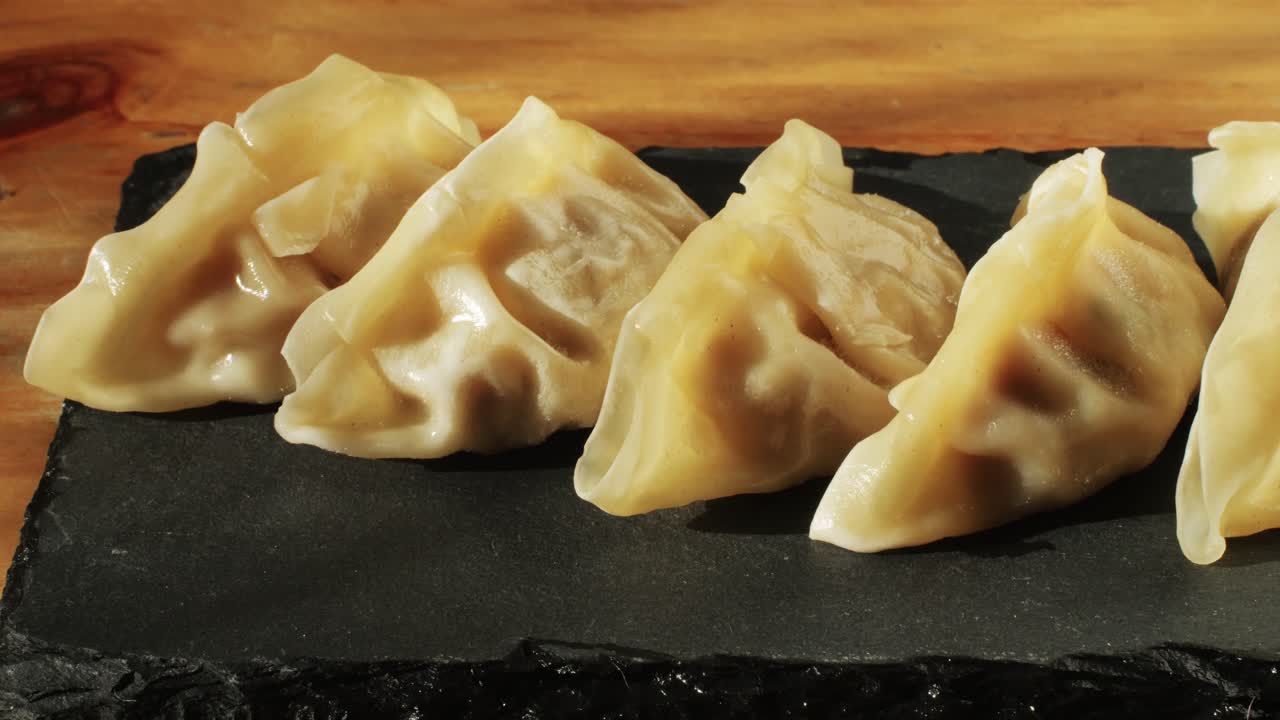 Japanese gyoza on black plate close-up. Dumplings with meat pouring red sweet chilli sauce. Cooking at cafe, restaurant. Homemade. Delivery.High quality 4k footage