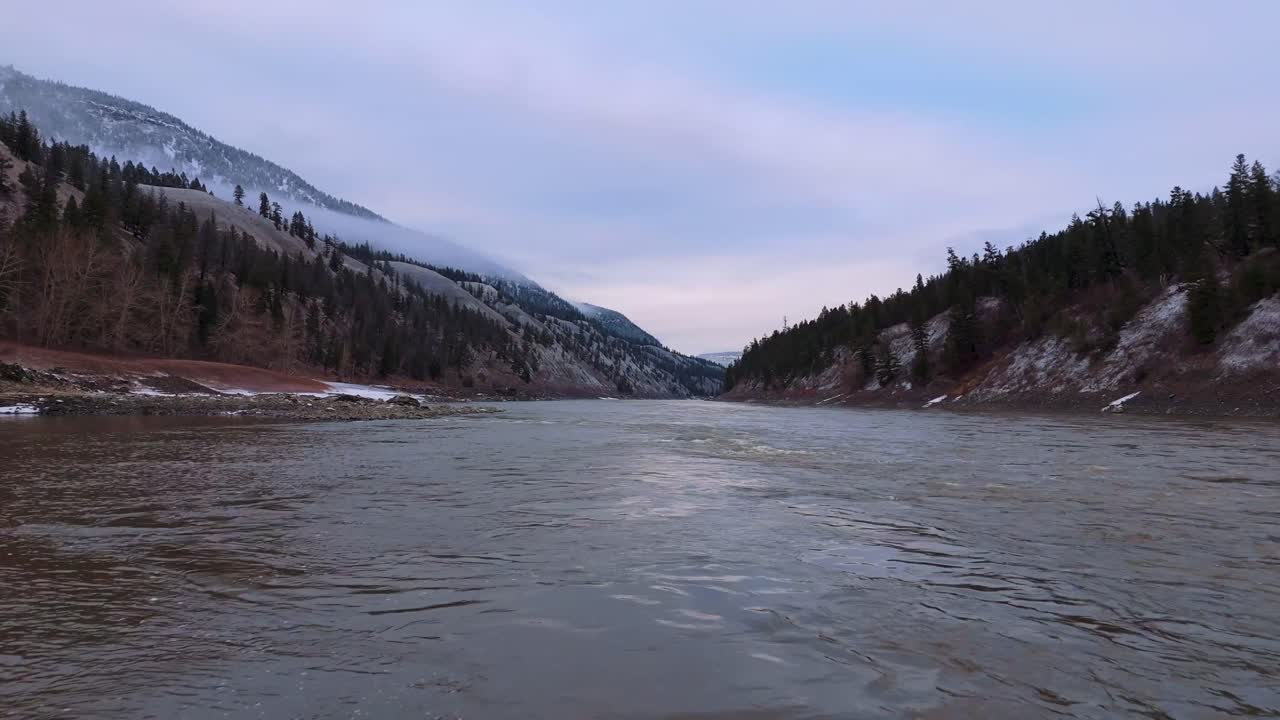 4K CGI aerial of a wild Canadian river winding through snowy mountain peaks, capturing raw natural beauty and pristine wilderness.