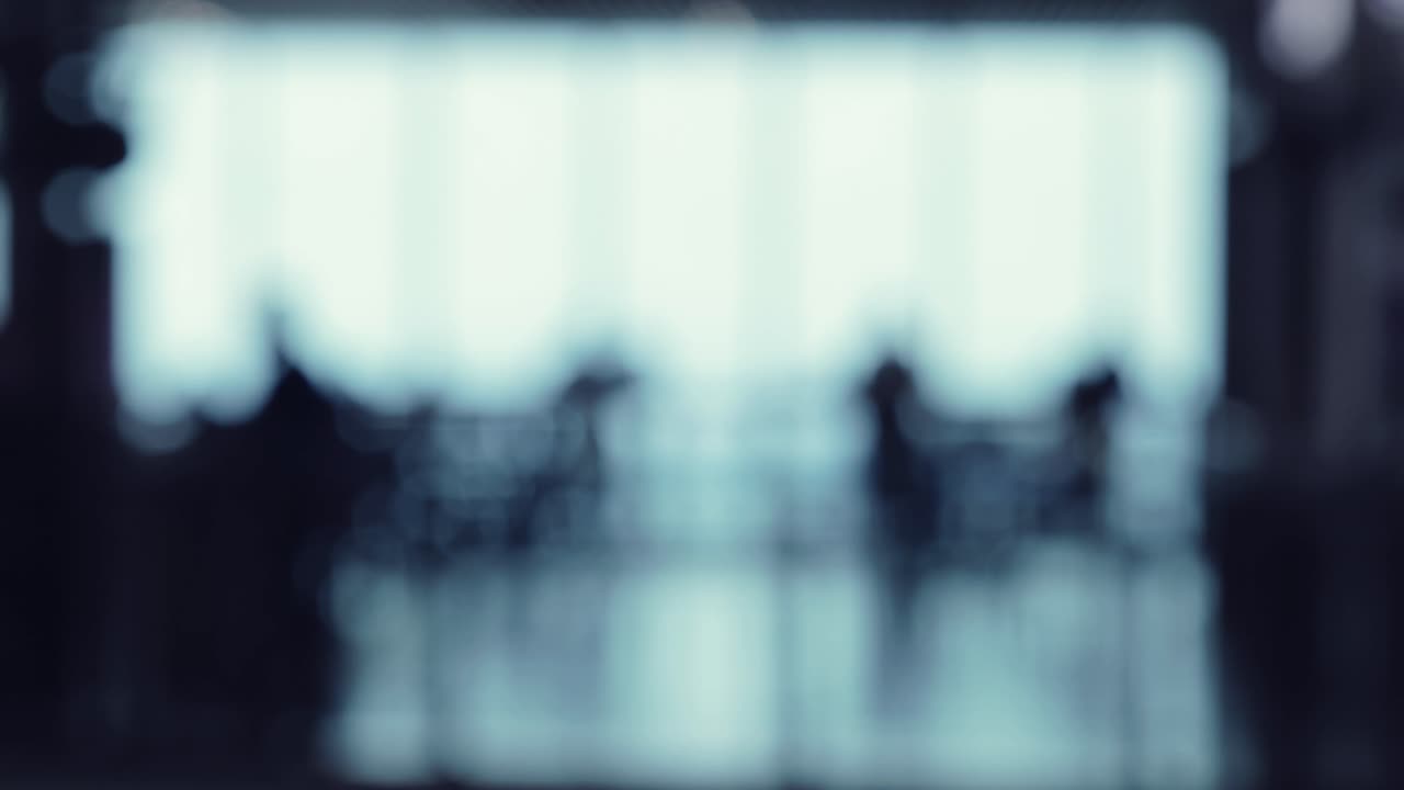 A defocused shot of many silhouettes of people walking around in a food ...