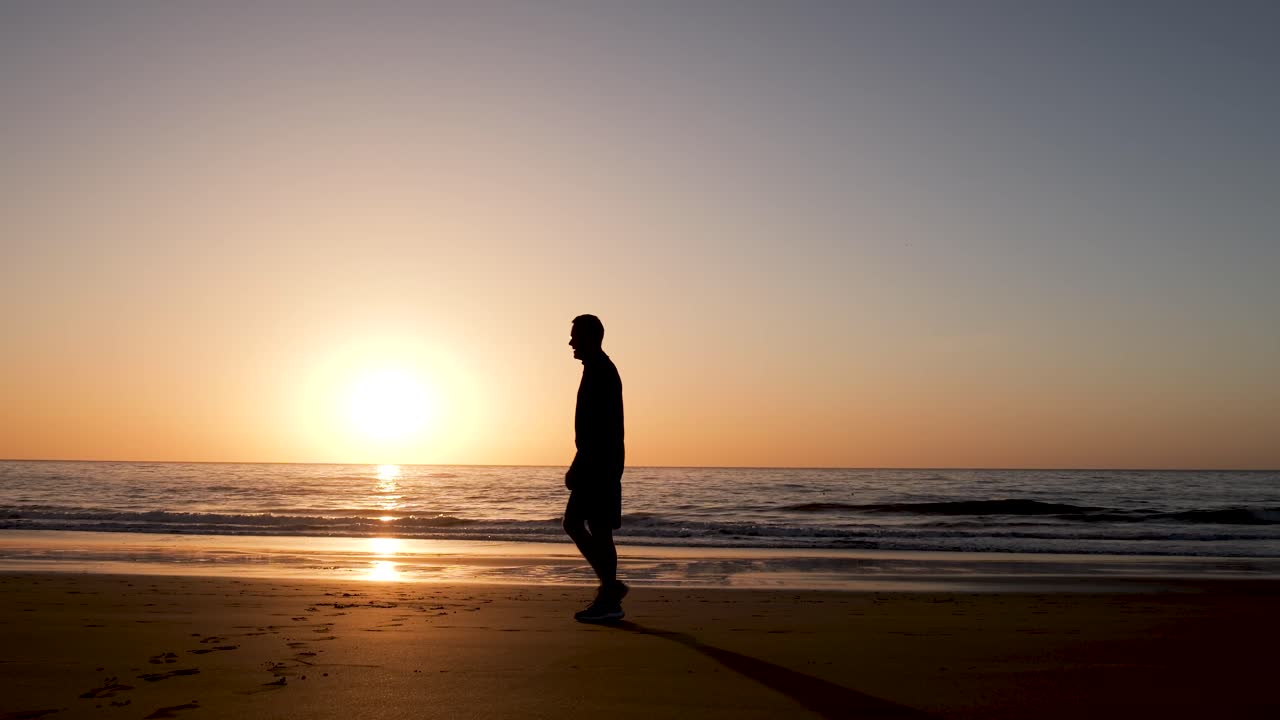 해가 지면 해변을 고 있는 남자
