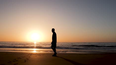 man walking on the beach at sunset