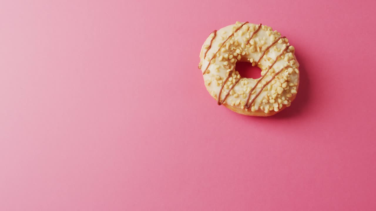 video de una rosquilla con glaseado en fondo rosa