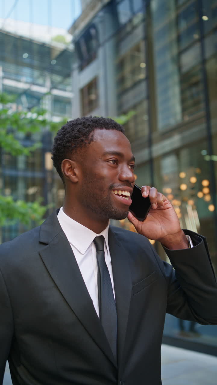 Vertical Video Shot Of Smiling Young Businessman Wearing Suit Talking On Mobile Phone Standing Outside Offices In The Financial District Of The City Of London UK Shot In Real Time 1