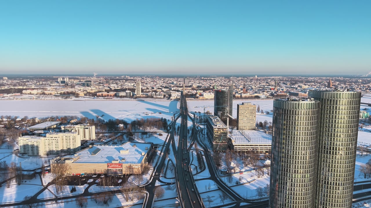 Aerial view of Riga city in winter with snowy rooftops and main road leading through urban skyline, bright, clear day ideal for travel, transport, and city life concepts