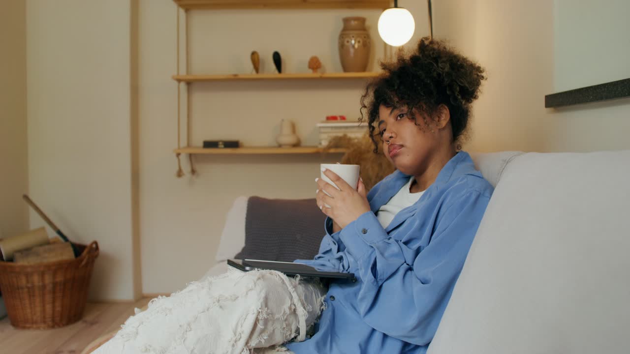 Donna che si rilassa su un divano con una tazza di caffè e un tablet