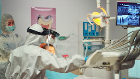 Little-girl-wearing-ppe-suit-looking-in-the-mirror-after-dental-intervention