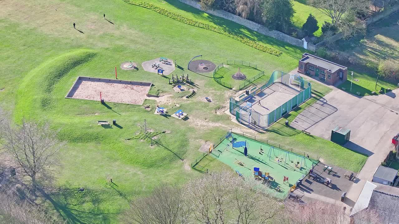 Wide drone overview of historic Elsecar park area with play structures and sand pits