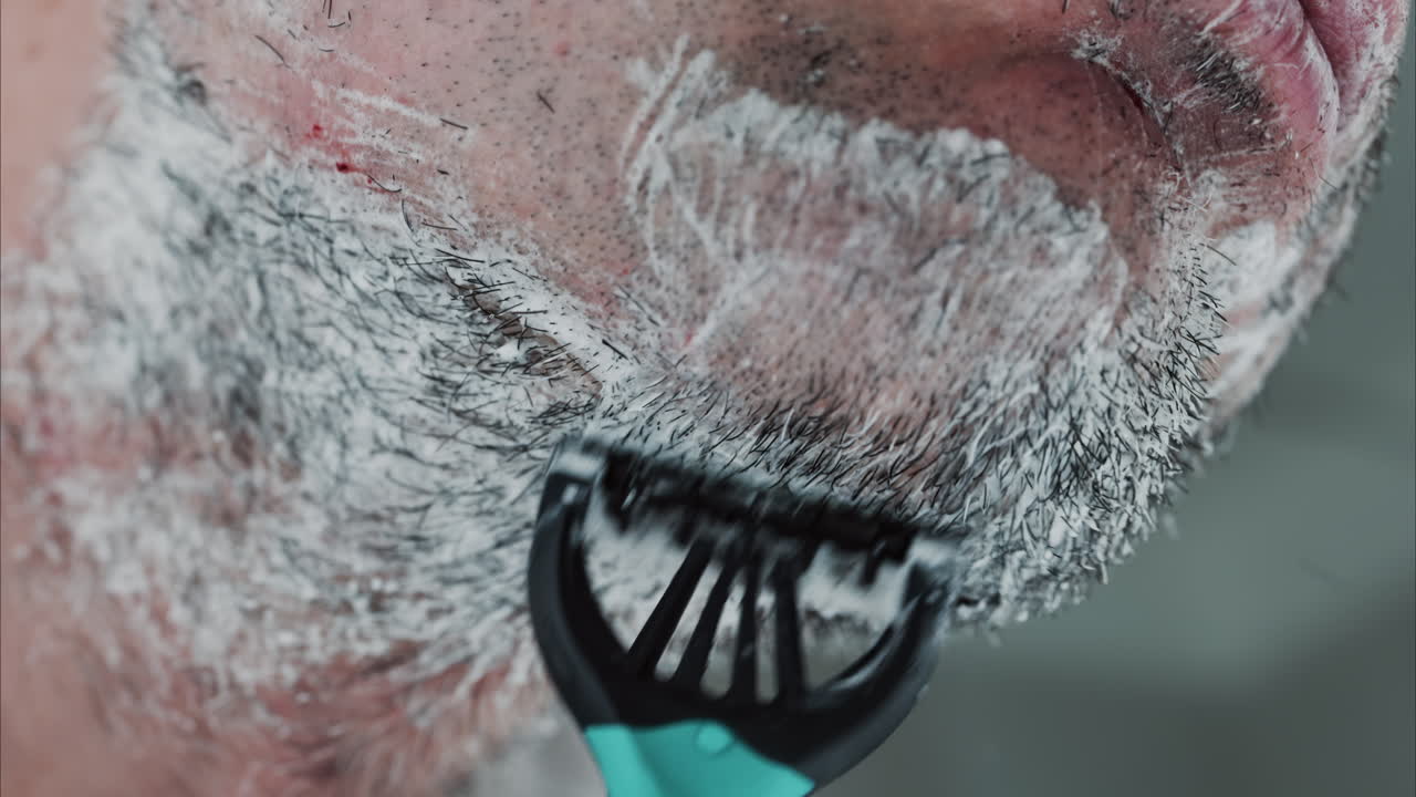 Close-up van een man die zijn baard scheert met een scheermes