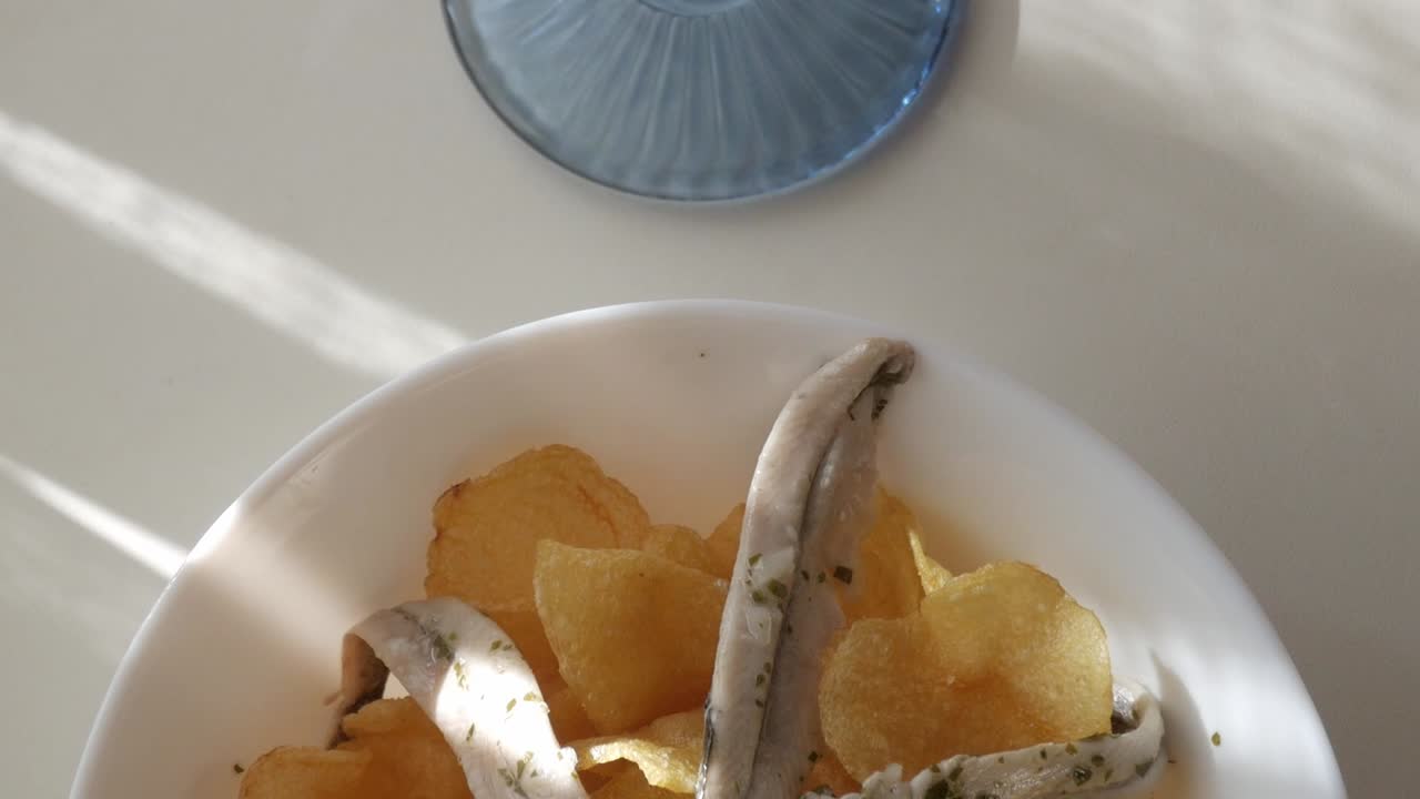 Fresh and crispy potato chips served with flavorful boquerones and vermouth