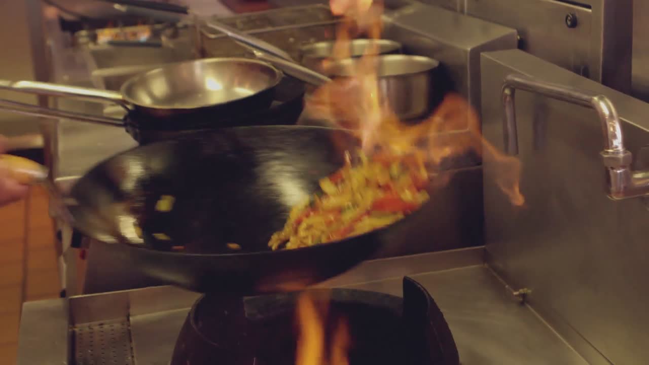 Chef che fa saltare in padella un piatto fiammeggiante