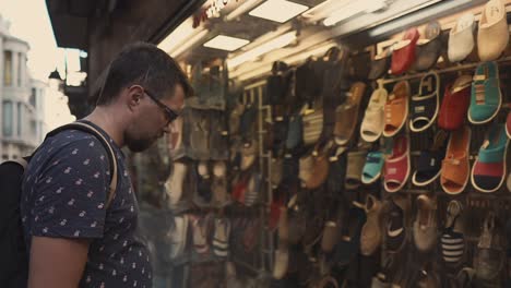 hombre mirando sandalias en una ventana de una tienda