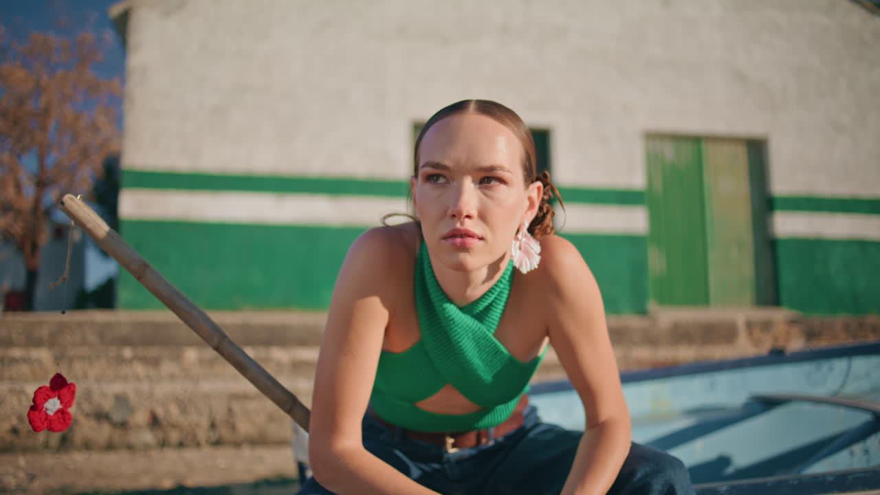 아름다운 여자가 강변의 집에서 휴식을 취하고 있습니다. 차분하고 세련된 소녀가 배에 앉아 있습니다.