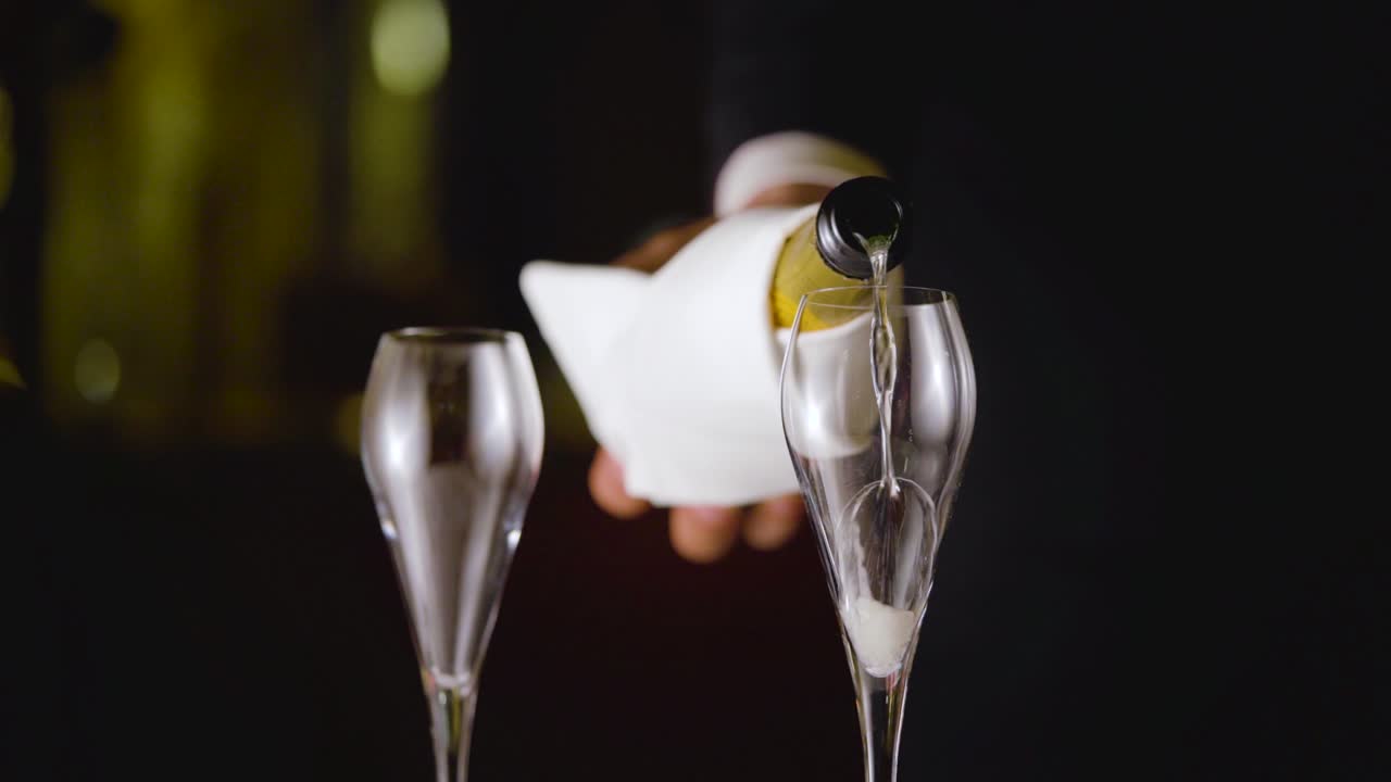 A waiter is pouring champagne elegantly in slow motion