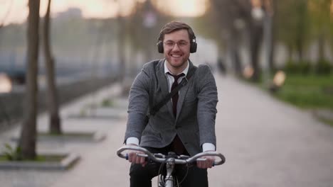 Joven-Empresario-Sonriente-En-Bicicleta-Escuchando-Música-Y-Sonriendo