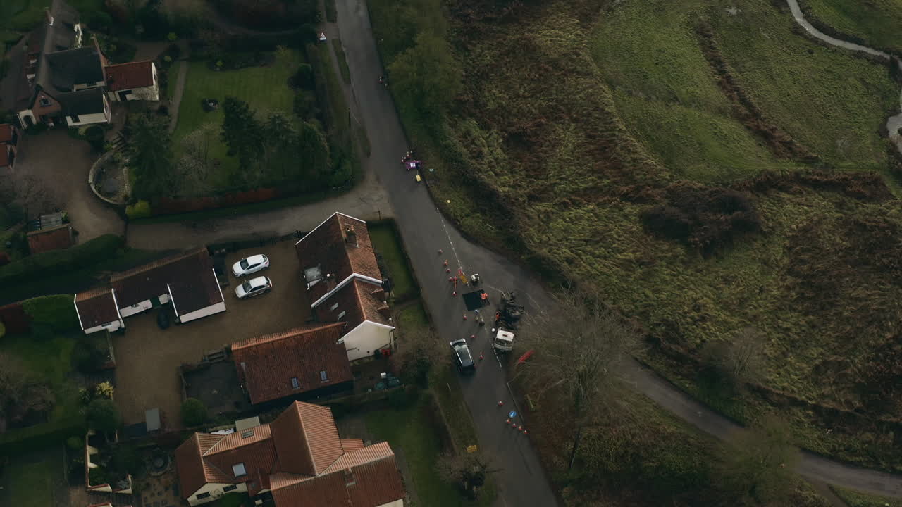 Aerial drone shot following a car as it passes by local houses and roadworks