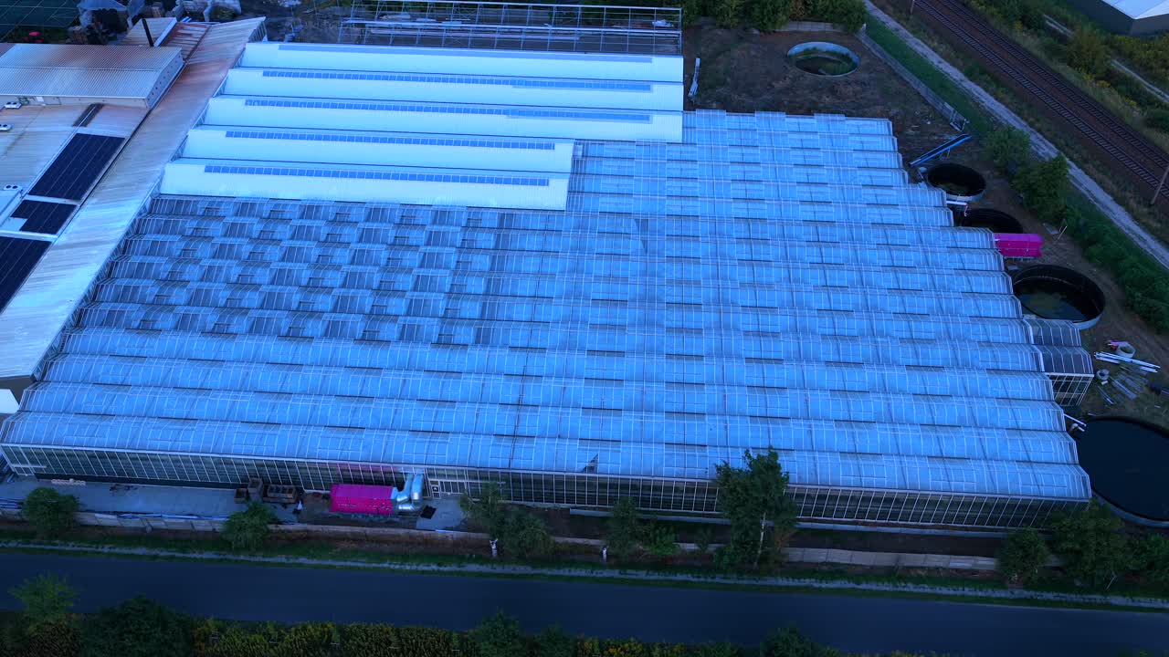 Aerial night view of illuminated greenhouses in Warsaw, Poland. Large-scale plant cultivation facility showcasing agriculture, farming technology, and sustainable food production
