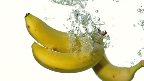 bananas plunging into water on white background