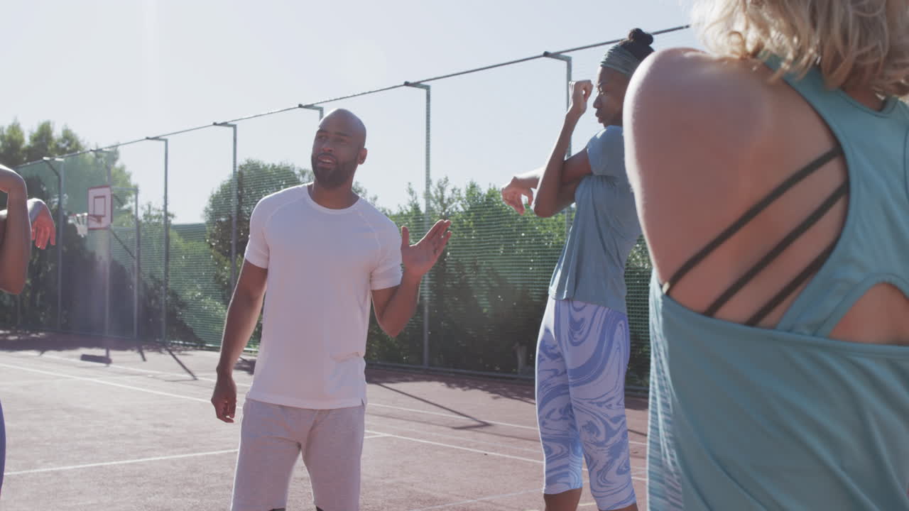 Biracial man discusses strategy on an outdoor basketball court