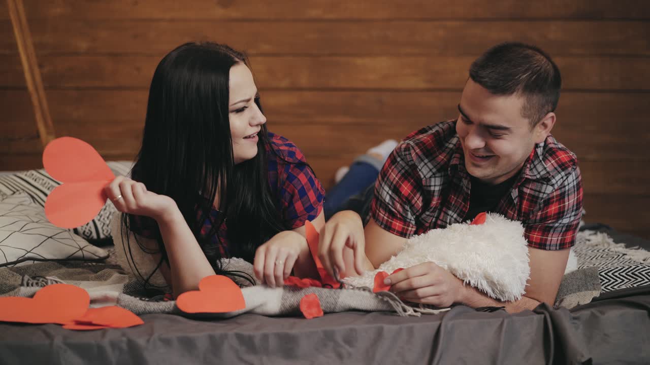 enamored man and woman are throwing into each other hearts by handmade on the bed on Valentine's Day