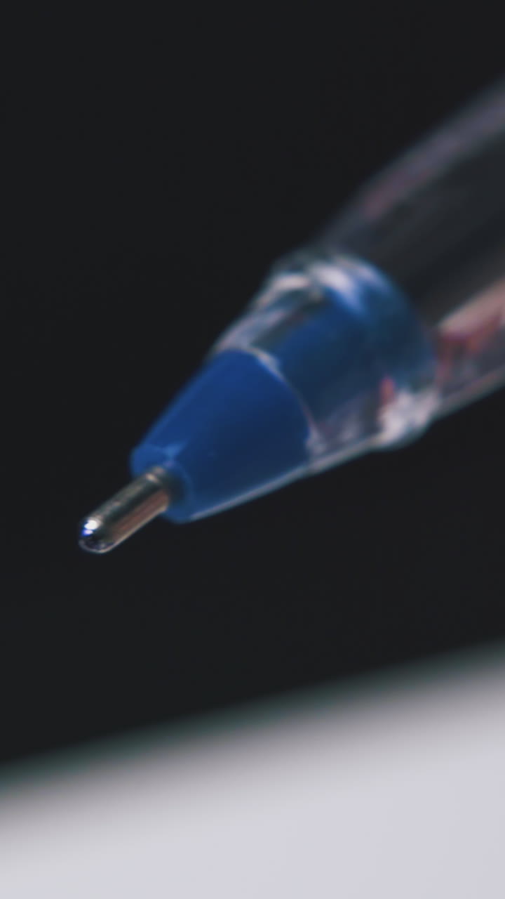 young person takes off blue plastic cap from new ball pen on blurred background extreme close view