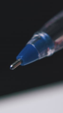 young person takes off blue plastic cap from new ball pen on blurred background extreme close view