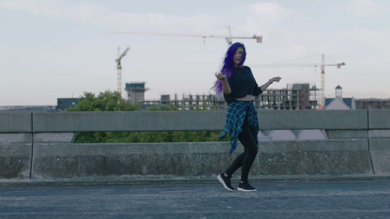 bailarina hermosa bailarina joven realizando baile callejero de estilo urbano en la ciudad practicando movimientos de estilo libre con cabello púrpura