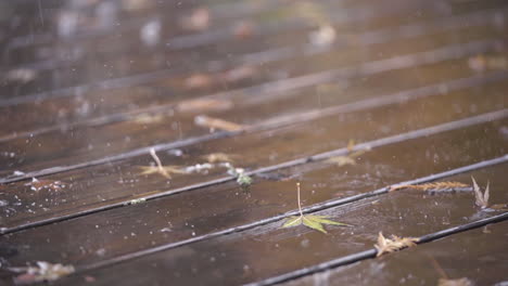 slow motion close up of raindrops hitting wooden deck