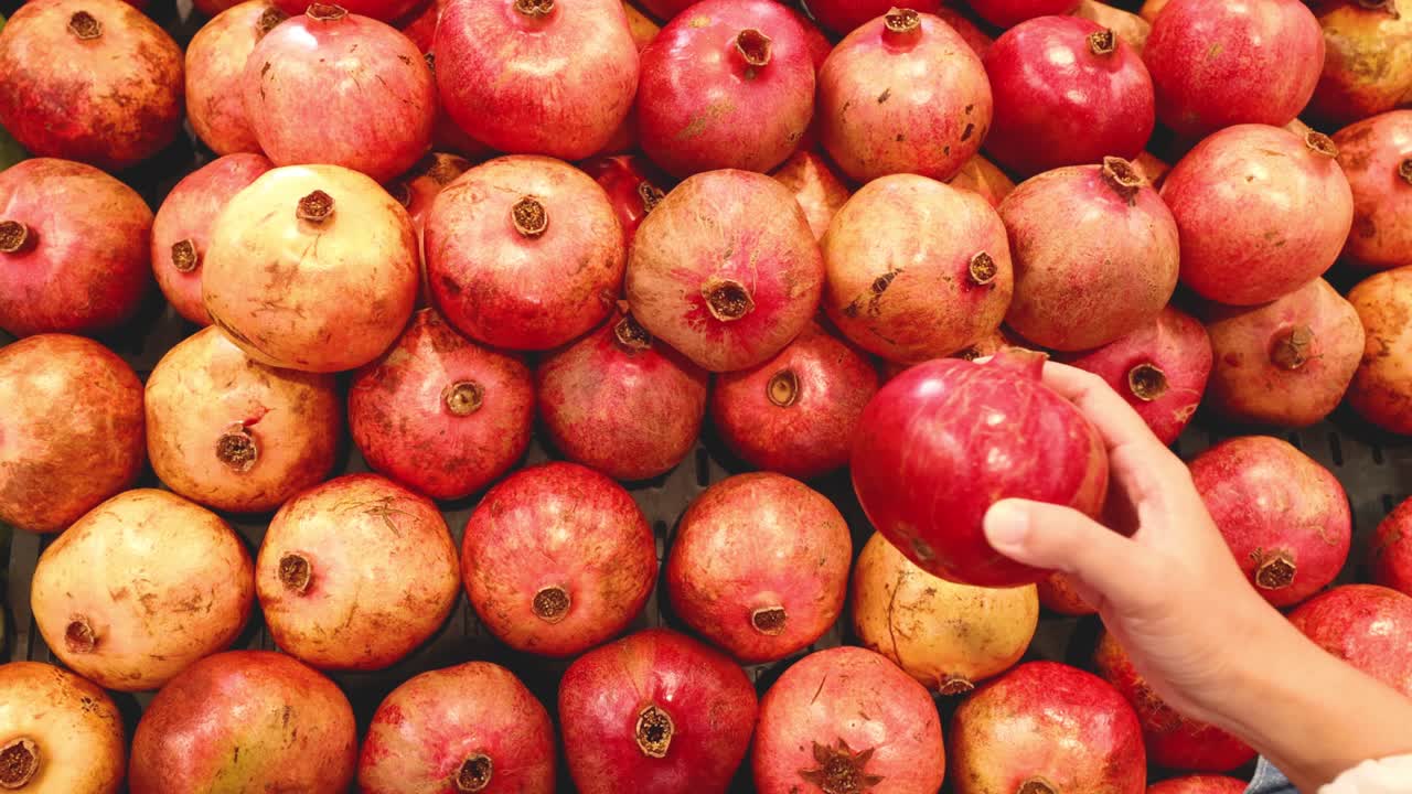 Hånd plukker granatæble fra frugtudstilling