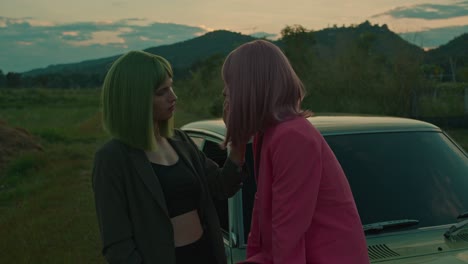 two women beside a retro car at sunset