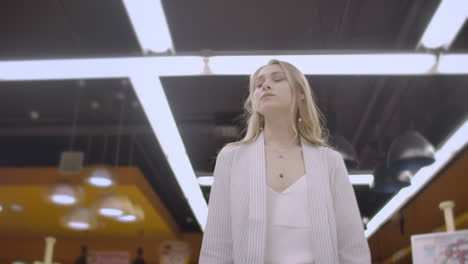 A-woman-buyer-in-a-grocery-store-with-a-basket-walks-between-the-shelves-and-counters-looking-at-the-goods-and-products-a-woman-in-a-supermarket