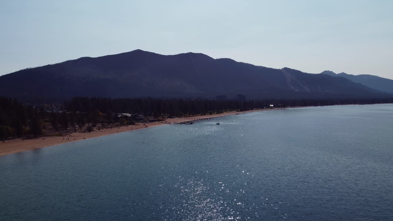맑고 화창한 날 레이크 타호, 네바다 해변, 천국의 산을 배경으로 반시계 방향으로 드론 촬영