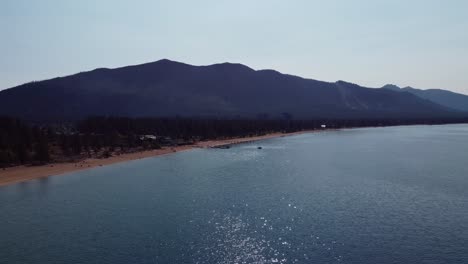 toma de drones en sentido antihorario del lago tahoe, la playa de nevada y la montaña celestial al fondo en un día claro y soleado