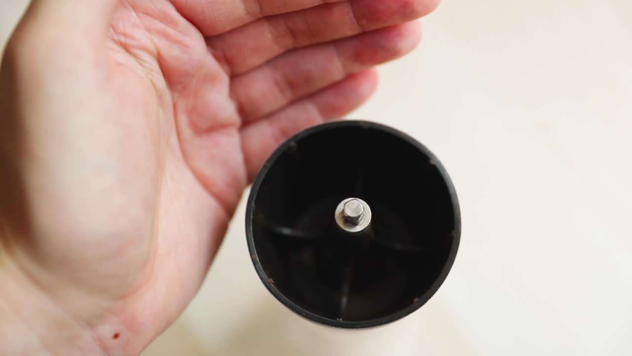 커피 준비 종이 봉지에서 핸드 그라인더에 곡물을 뿌리는 모습