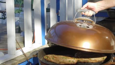 Lifting-the-lid-on-a-BBQ-showing-tri-tips-cooking