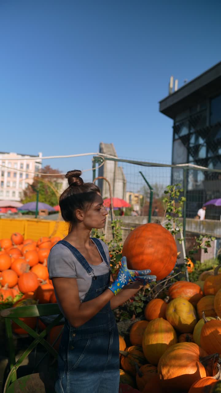 mujer sosteniendo una gran calabaza en un mercado de otoño