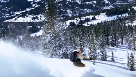 male snowboarder riding down fresh powder snow followed blue sky steep turns vail pass colorado