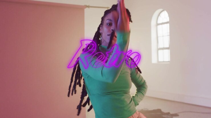 Woman beginning by extending right arm, dancing in set neon Retro shifting over torso fashion shoot