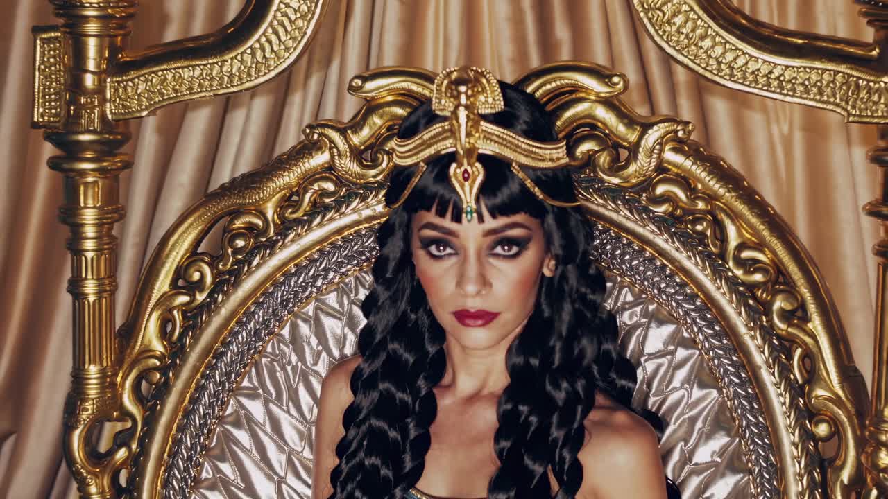 A regal, Cleopatra-inspired video scene with a woman in ornate attire, captured from a front-facing