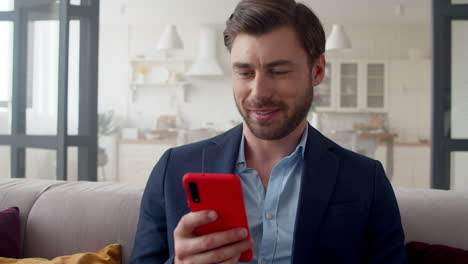 Smiling-business-man-reading-messages-on-phone-at-home