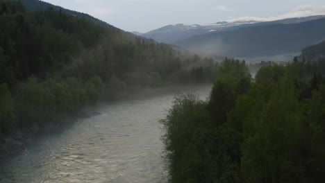 flight over a foggy river. the mist is hanging low over the landscape creating a dark mystical mood over the whole scene.