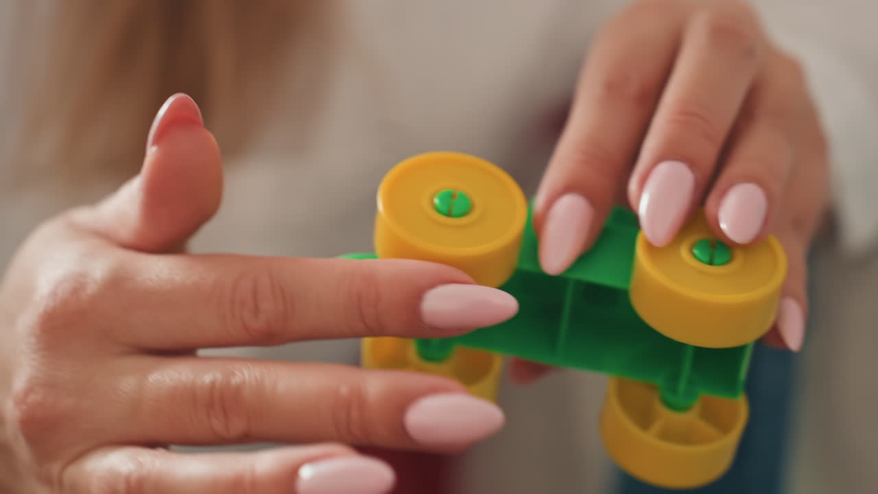 Mother fixes vehicle. Parent diligently mends toy car. Gentle mother carefully restores toy vehicle. Maternal figure attentively repairs small toy automobile with love and patience