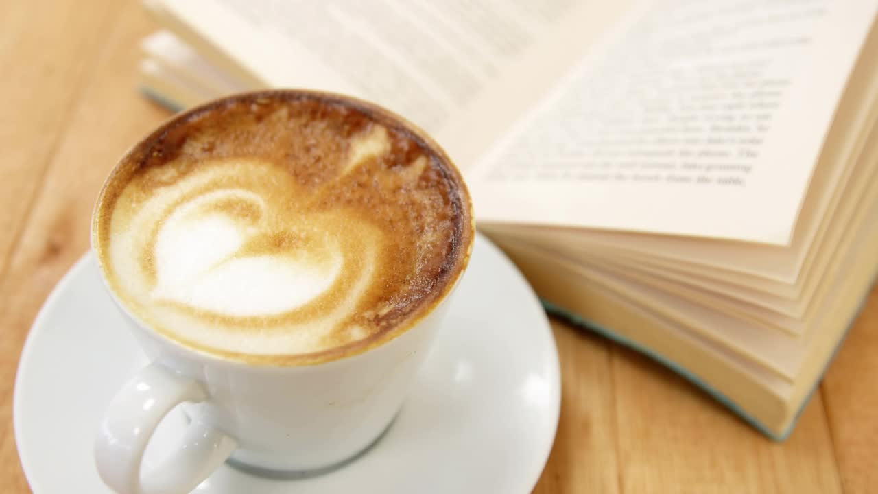 Partículas subindo acima da xícara, girando sobre a espuma do coração, flutuando pelas páginas do livro, mostrando a magia do café
