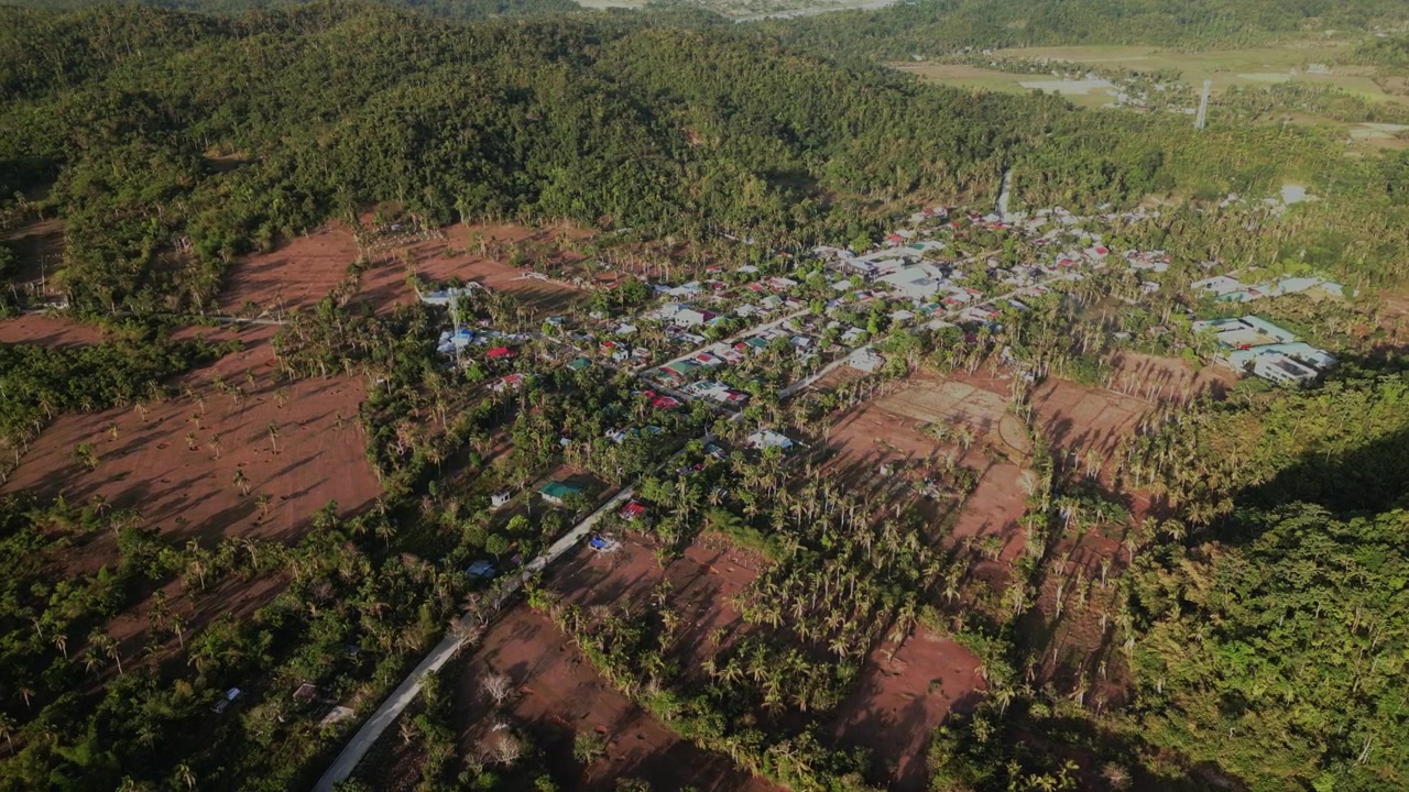 Naturskøn luftoptagelse i kredsløb over Hawan Grande, Catanduanes, der afslører en malerisk barangay-landsby midt i landbrugsjord, kokoslunde og frodig ø-grønt.