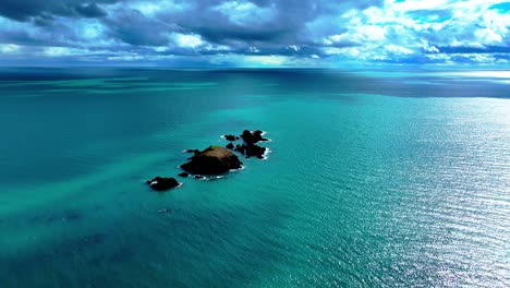 drone flying to islands with emerald green sea and dramatic skyline on the copper coast in waterford ireland in spring dramatic establishing shot